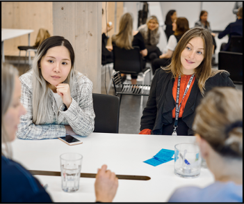Group of women engaged in a focused discussion around a table during a workshop session.