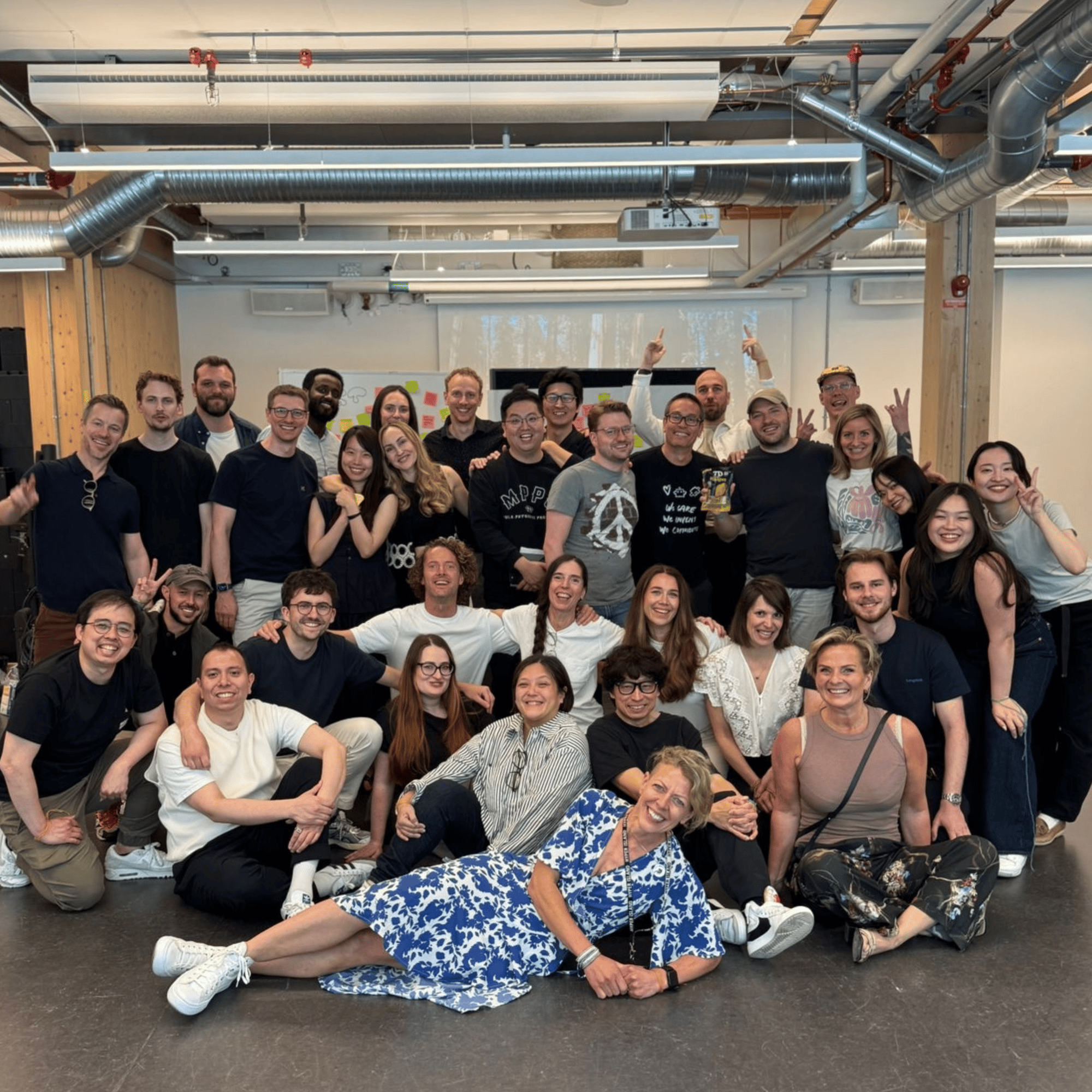 A large group of smiling professionals pose together in a modern office space, at Hyper Island in Stockholm