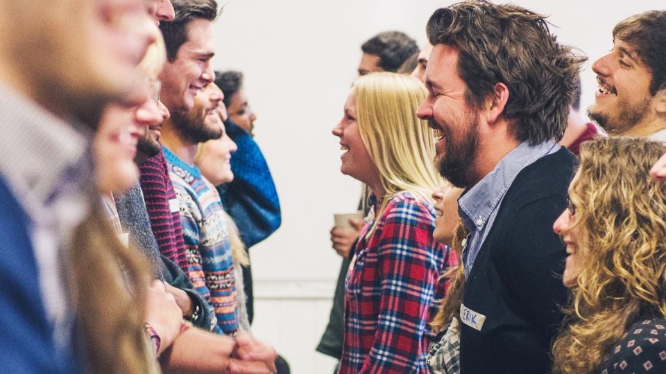 Two lines of students, approximately eight in each line, facing each other, some of them laughing.