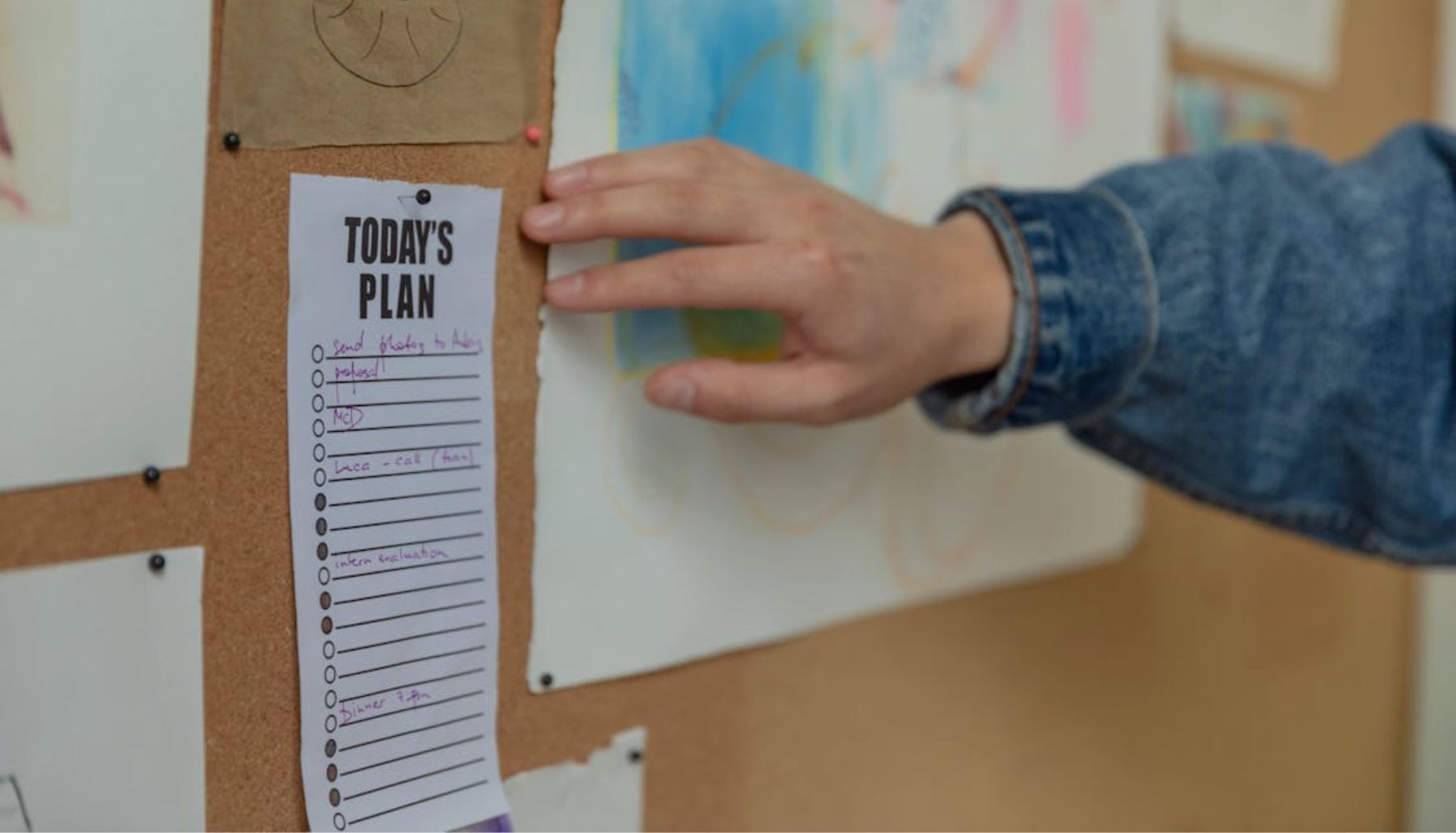  A close-up shot shows a person's left hand reaching towards a white sheet of paper that reads 