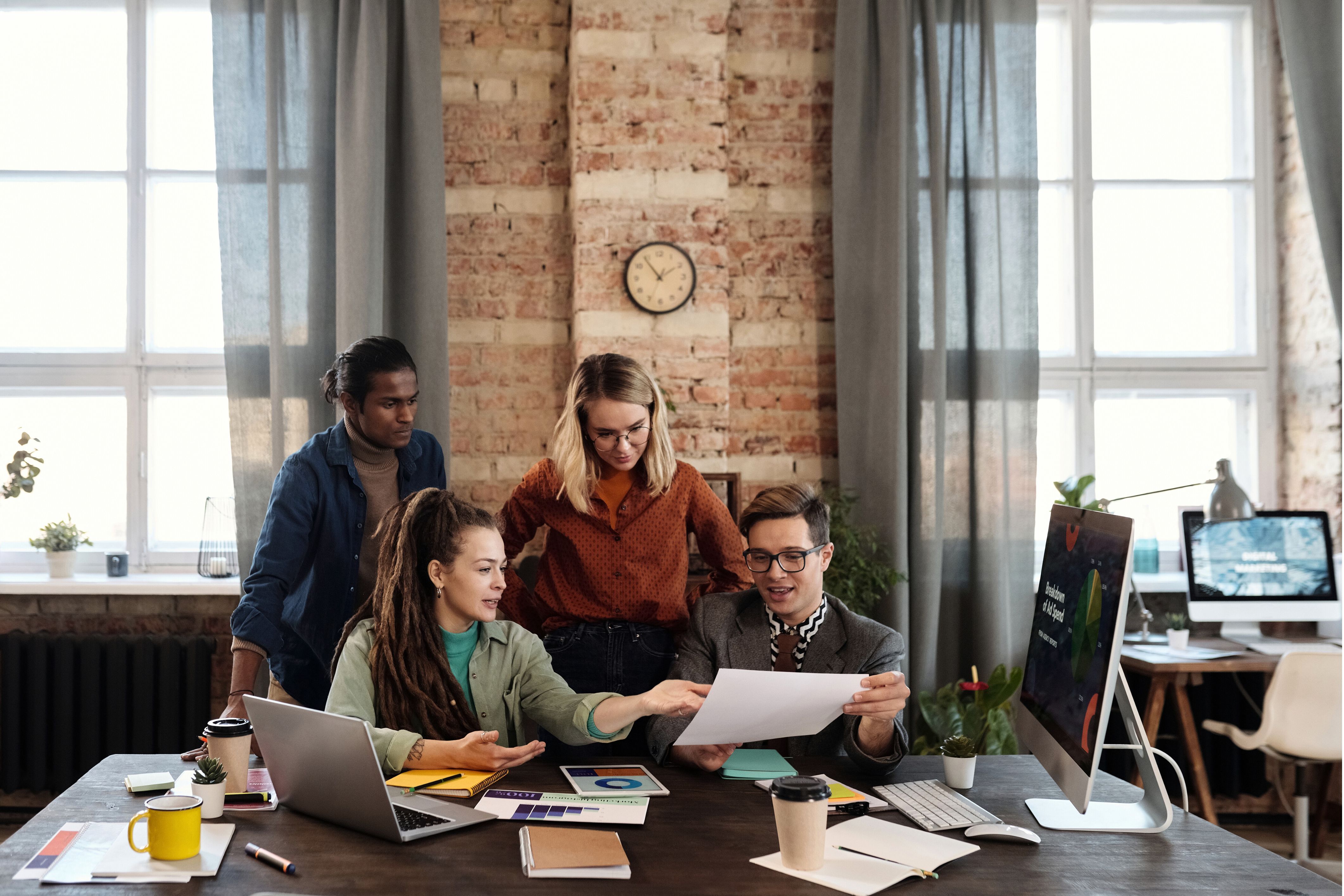 A diverse team of strategists gathered around a desk, reviewing market data and plans to build a new business development initiative.