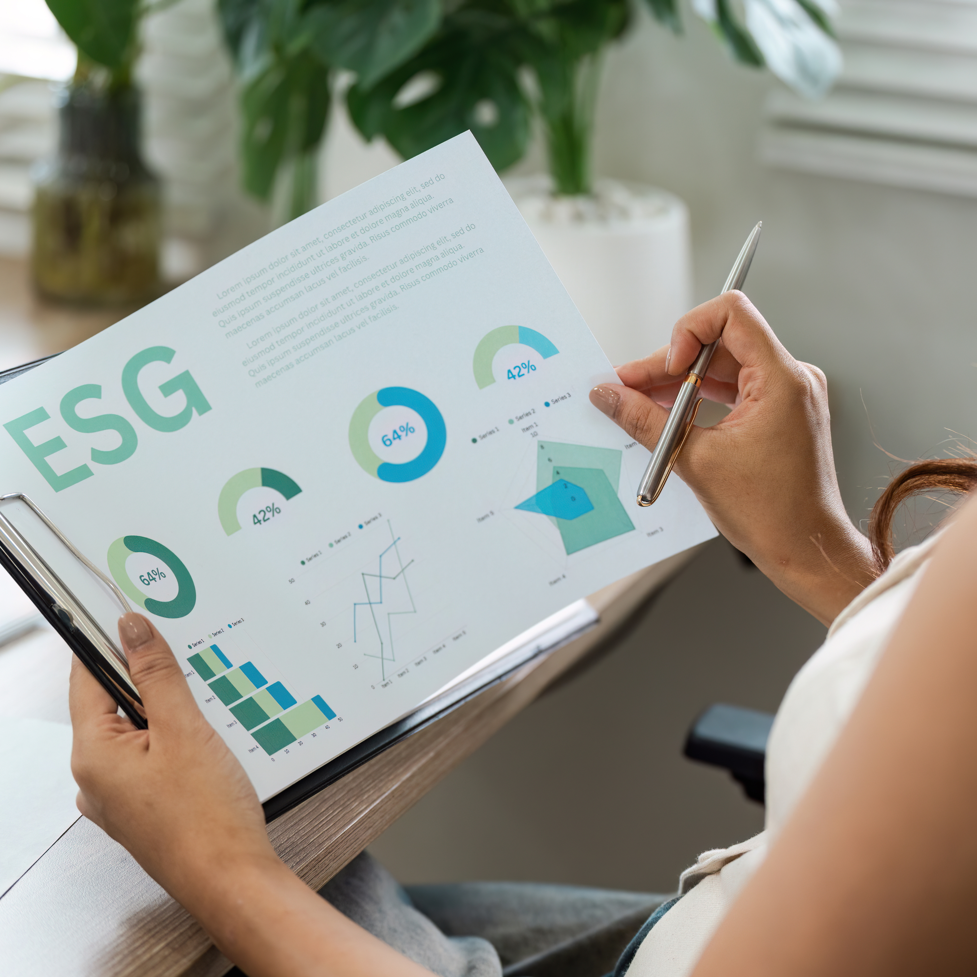 Woman holding a document with ESG (Environmental, Social, Governance) charts and graphs, reviewing sustainability data with a pen in hand.