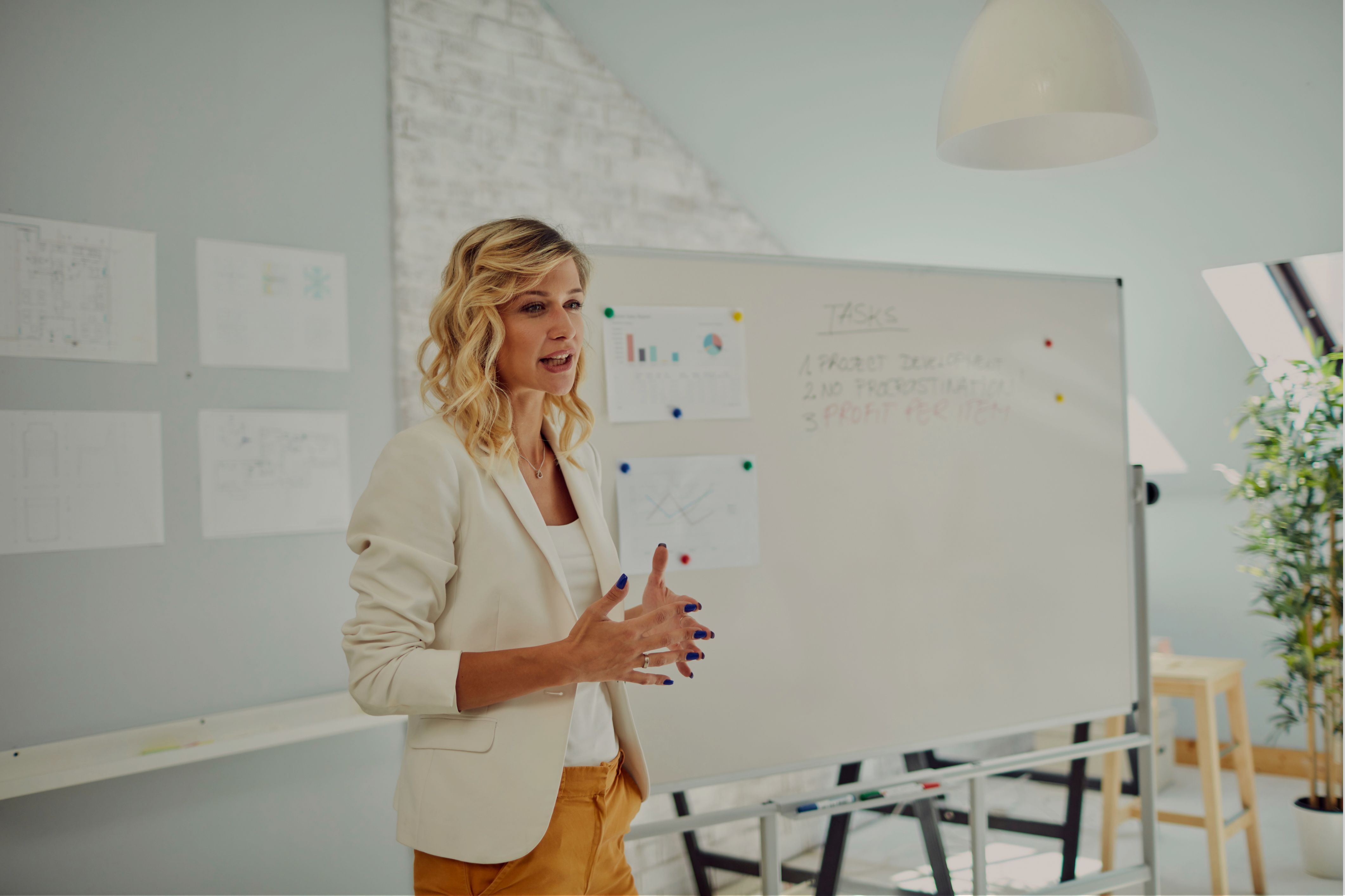 A business leader gives a presentation in front of a whiteboard during a team meeting.