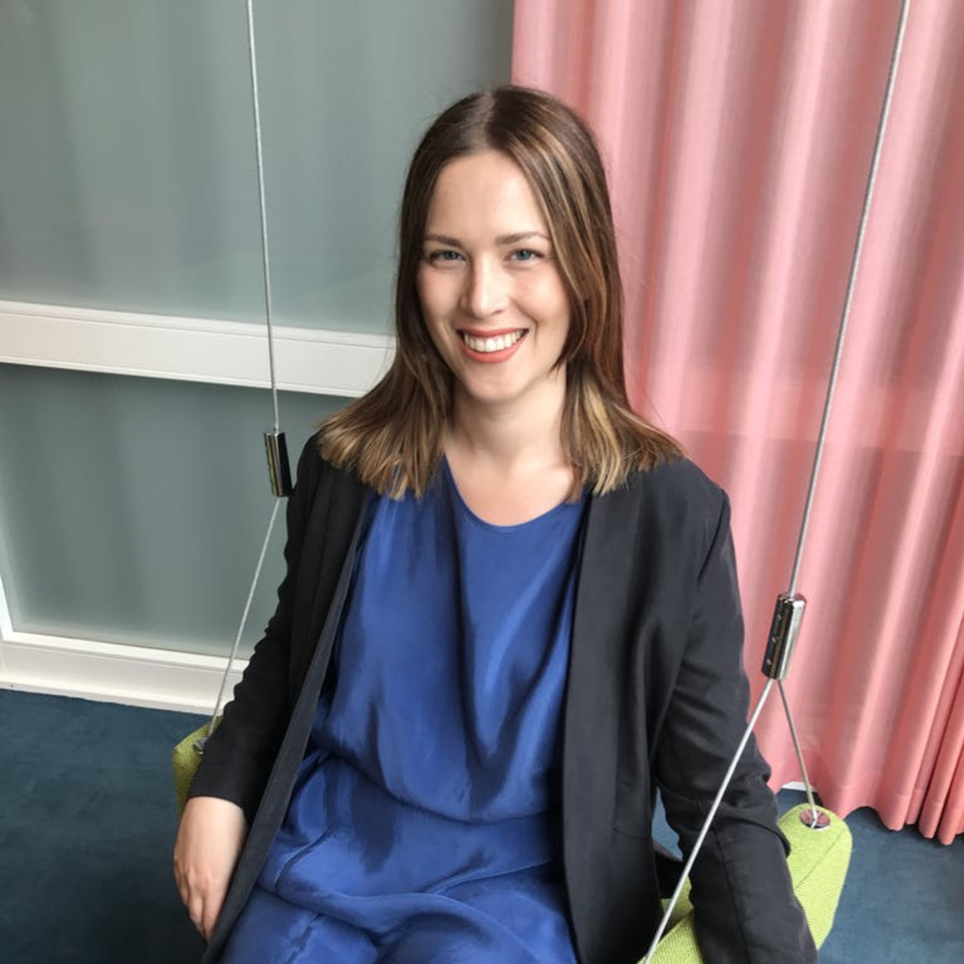 Maja, the subject of the blog post, smiling while sitting on a swing in an office environment.