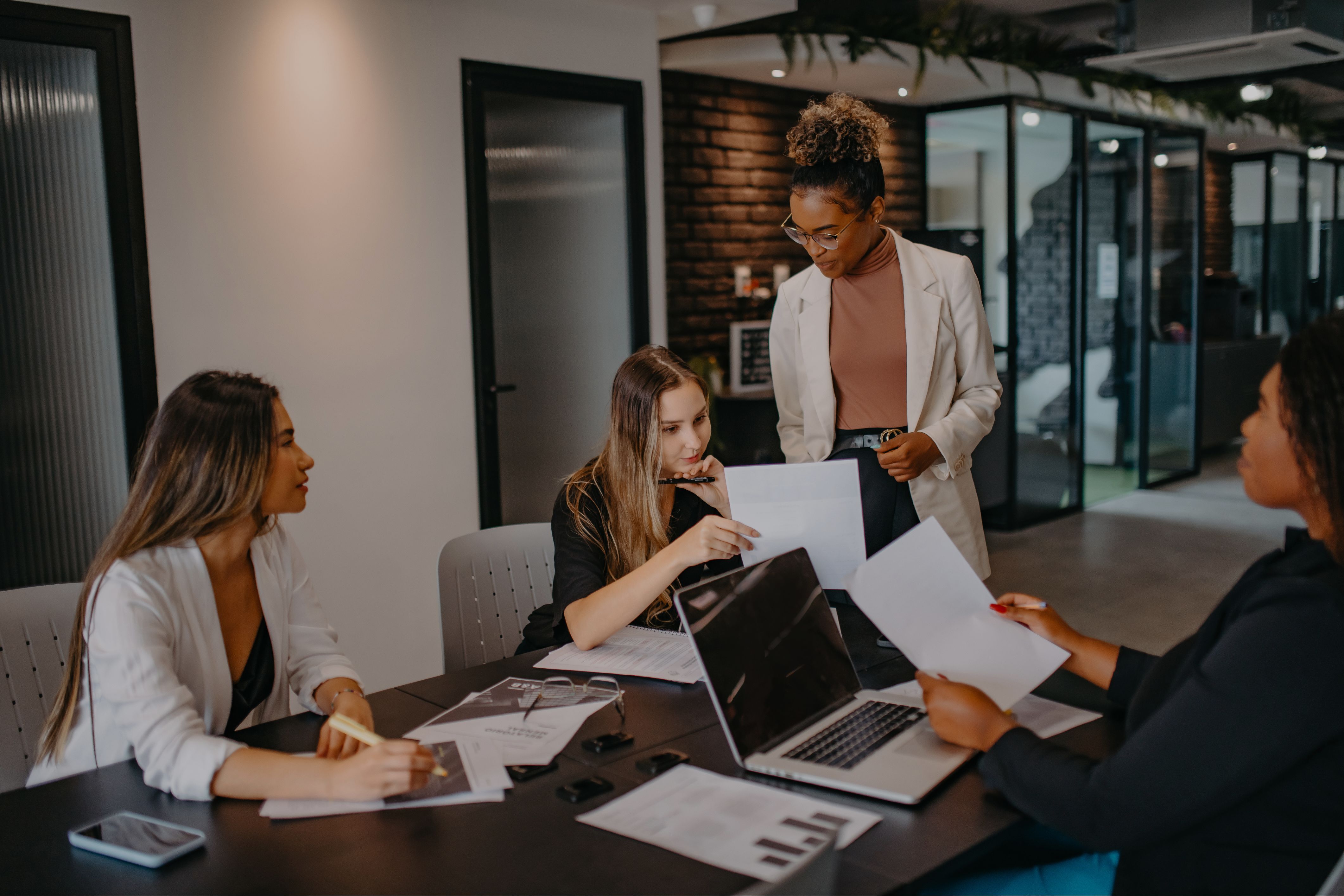 A marketing team collaborates in a modern conference room, analyzing documents and charts to discuss the latest marketing trends.