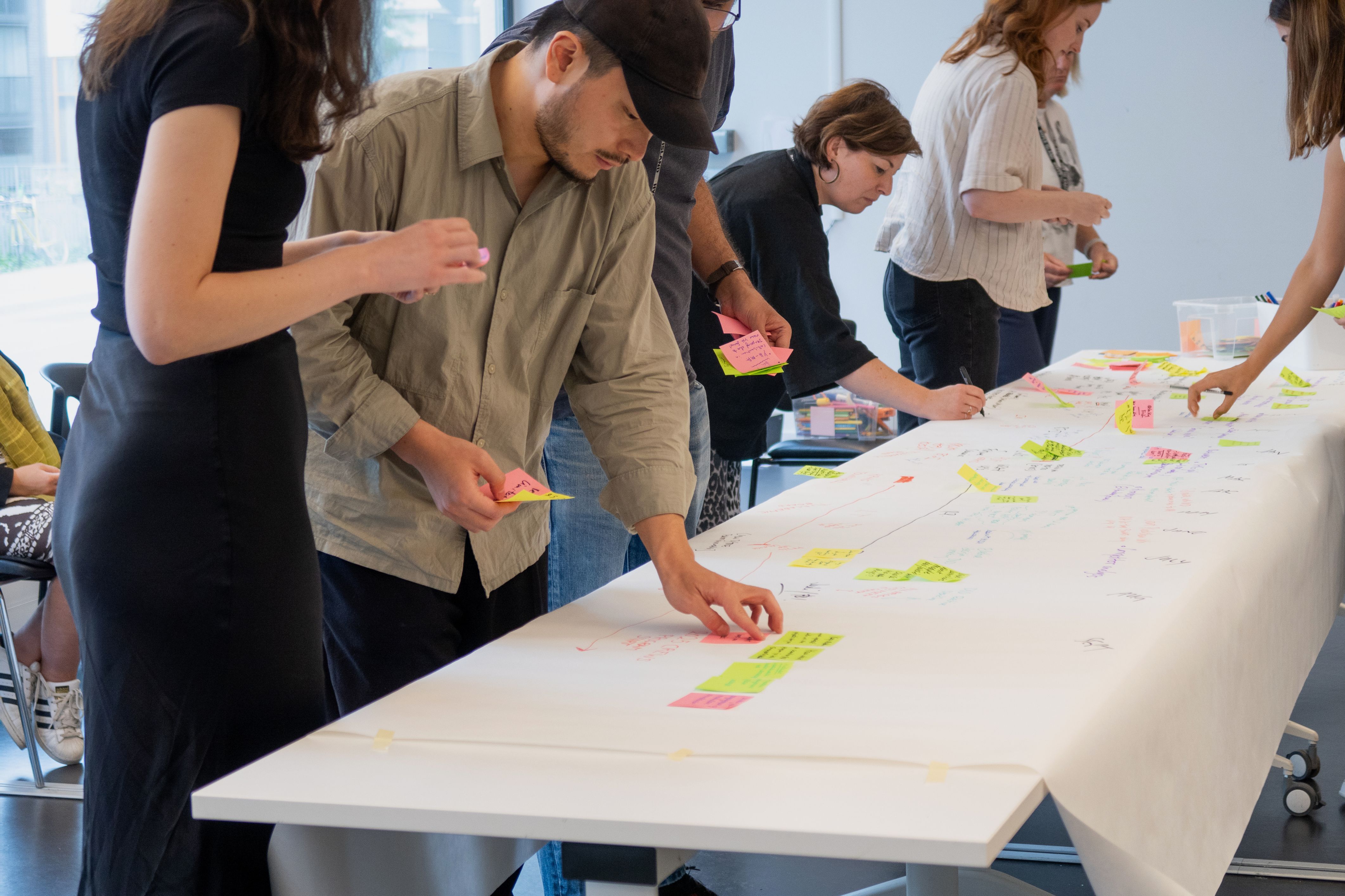  diverse team of professionals collaborating around a large table covered with strategy maps and sticky notes, illustrating modern, agile strategy trends in action.