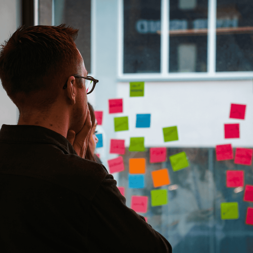 Person looking at a wall covered with colorful sticky notes during a Future Mapping session.