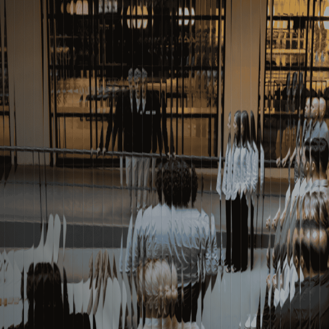 Image, with a glass effect applied to it, of people listening to a speaker at Hyper Island 